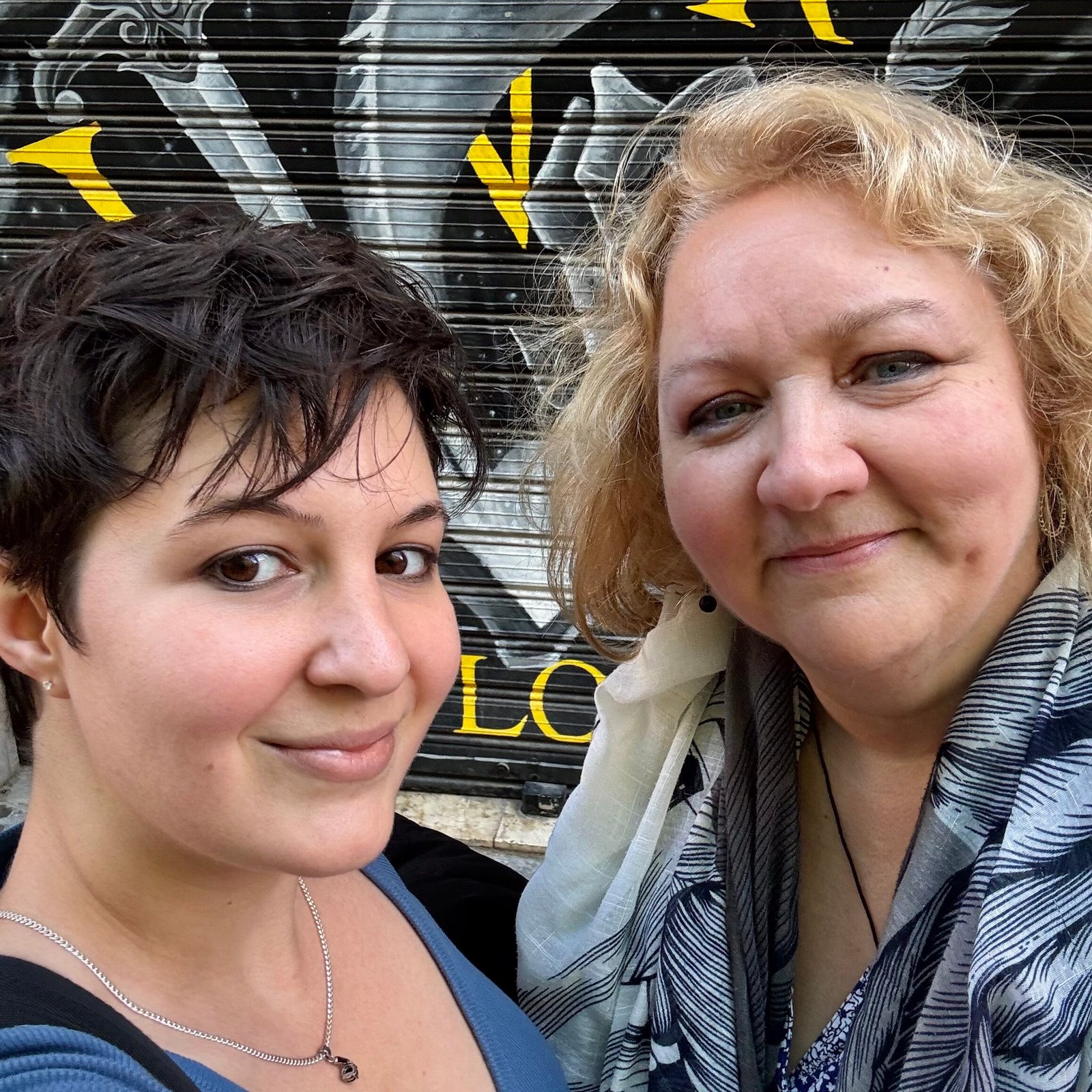 Selfie photo of Oriana (short dark hair) on the left and her mom, Kim (blonde, wavy hair), on the right, both smiling in front of Book Lovers Valencia's old Russafa bookstore location.